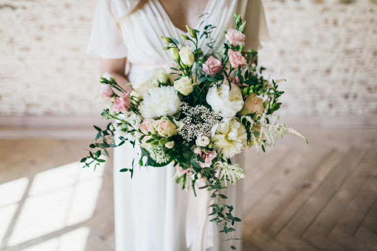 nevěsta drží svatební kytice v jemných odstínech