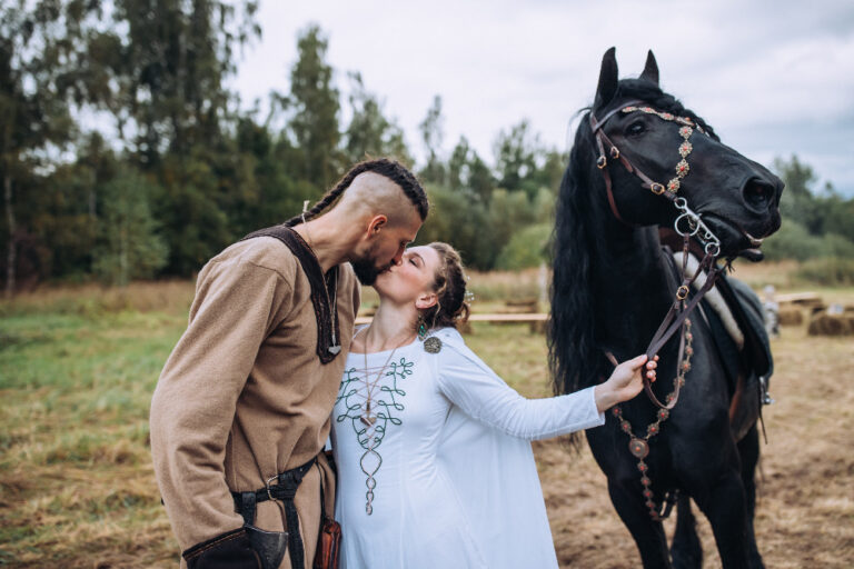 nevěsta a ženich se líbají ve vikingském oblečení vedle koně